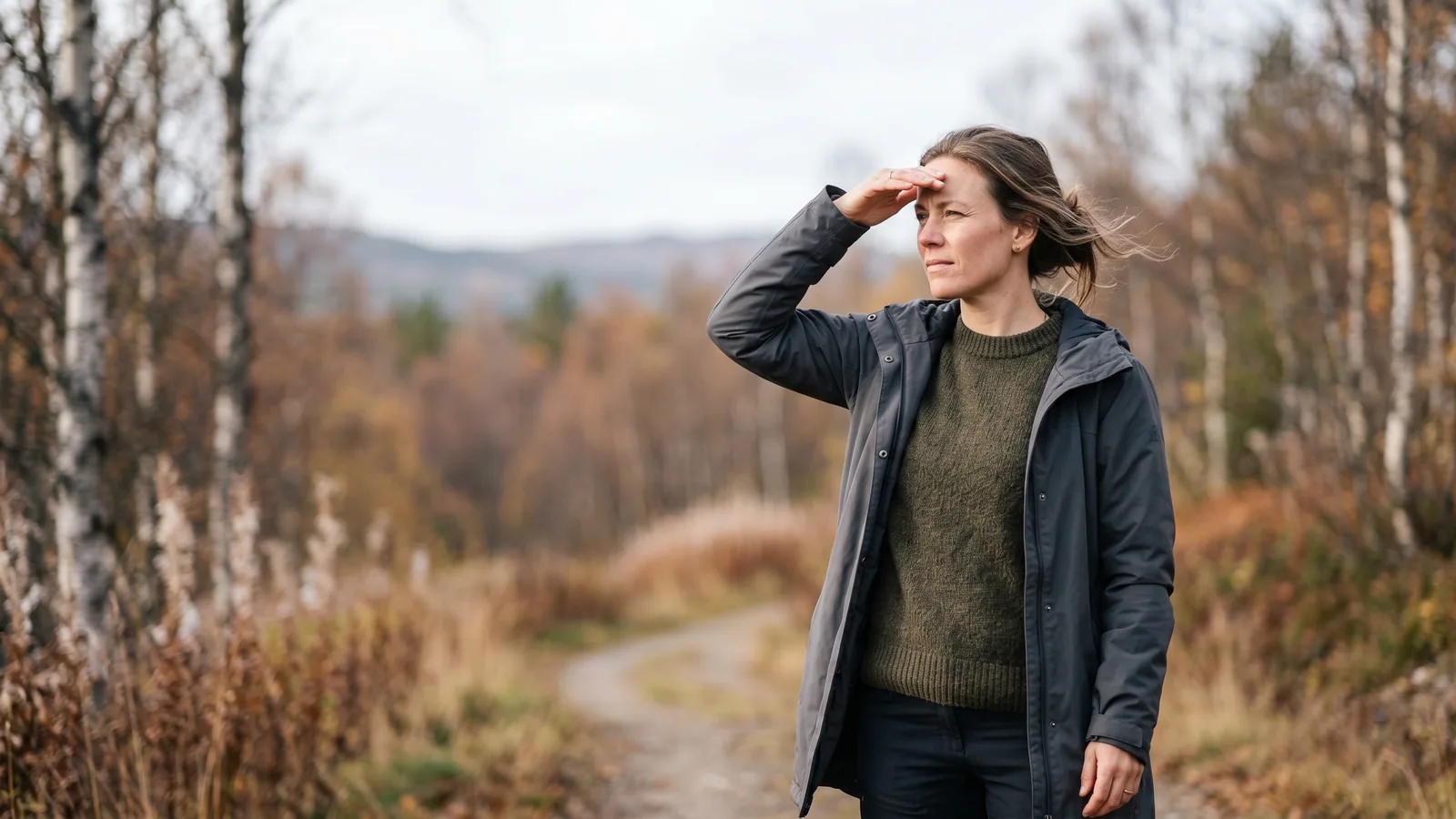 En person som kisar och håller upp handen för att skugga ögonen mot ett starkt ljus genom ett fönster