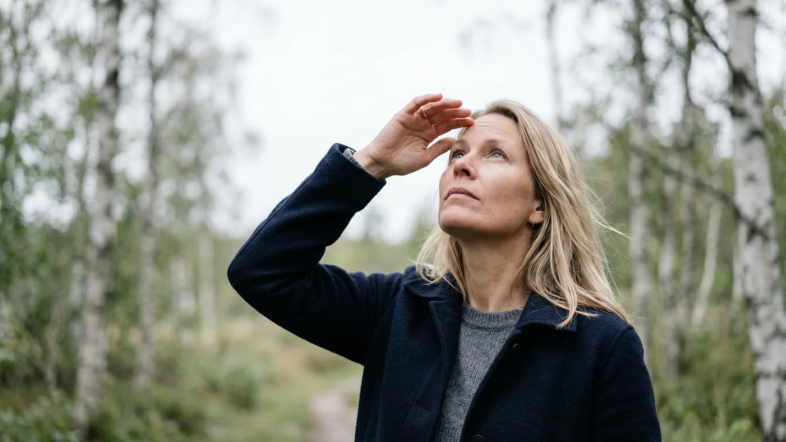 En person tittar mot en ljus himmel genom ett fönster och följer med blicken små grumlingar som driver förbi i synfältet.
