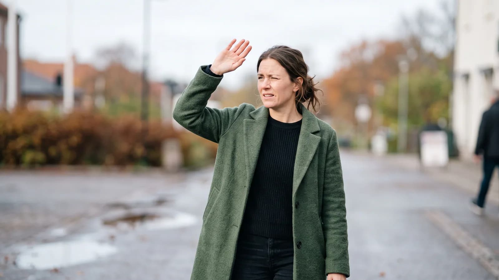 En person som kisar och håller upp handen för att skugga ögonen mot ett starkt ljus genom ett fönster